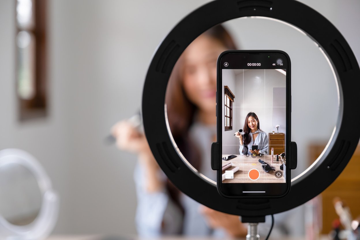 Woman live streaming while applying makeup.